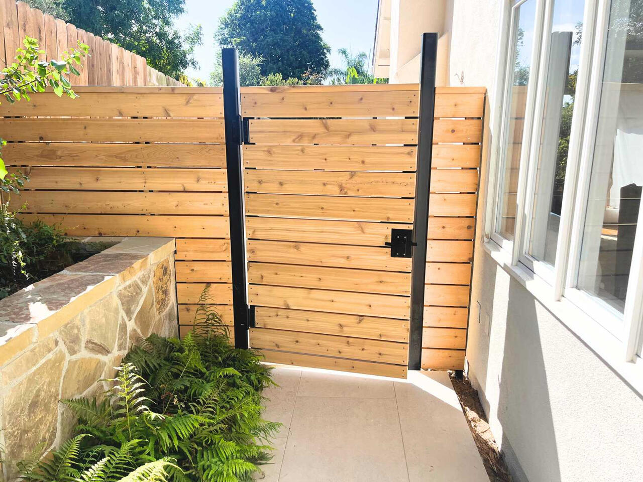 A completed gate and fence install, complete with custom black metal trim.