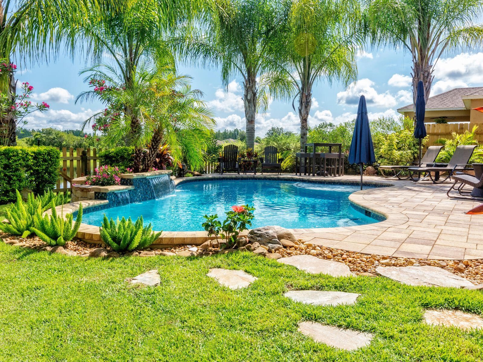 A beautifully remodeled and landscaped yard with stone work, a large pool, and accent pieces around the border.